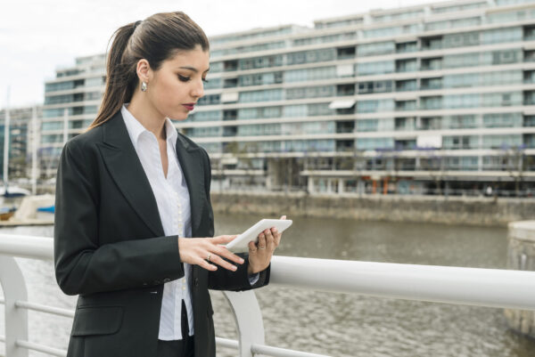 attractive-young-businesswoman-standing-near-railing-using-mobile-phone beginner machine operator training - Noble training group
