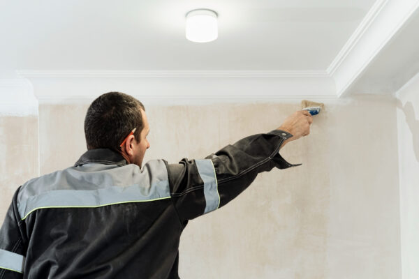Worker applies glue to the walls before wallpapering or primer on the walls. The idea of renovation and restoration of apartments, selective focus on the brush