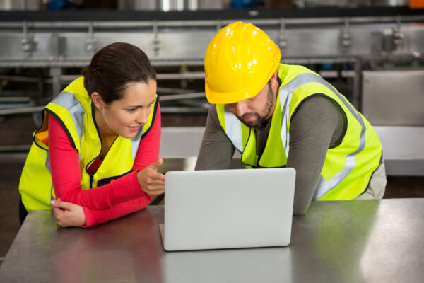 Male and female workers using laptop in factory bridging the skills gap- noble training group