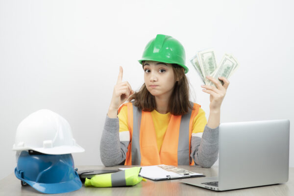 Worker female in orange vest and green helmet sitting at the desk high-paying trade jobs- Noble training group