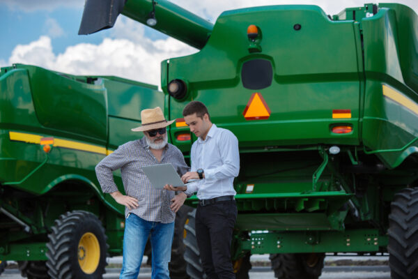 A farmer with a tractor, combine at a field in sunlight. Confident, bright colors machine tickets certification - Noble training Group